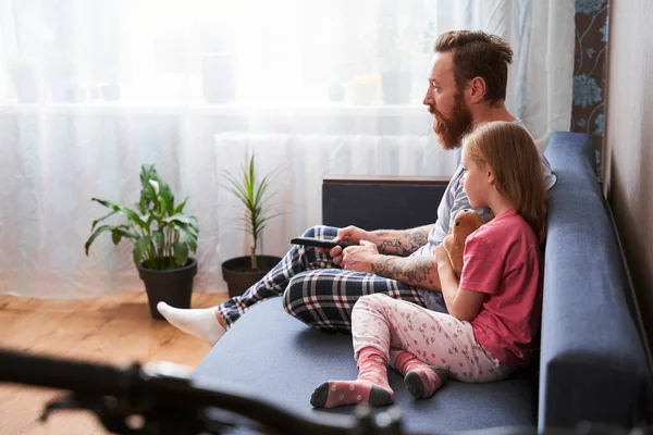 Ojciec i córka w piżamie siedzą na kanapie — Zdjęcie stockowe