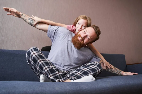 Girl flying on her handsome bearded father — Stock Photo, Image