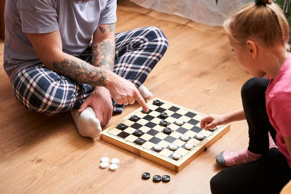 Father and his daughter wearing pajamas are playing checkers — Stock Photo, Image