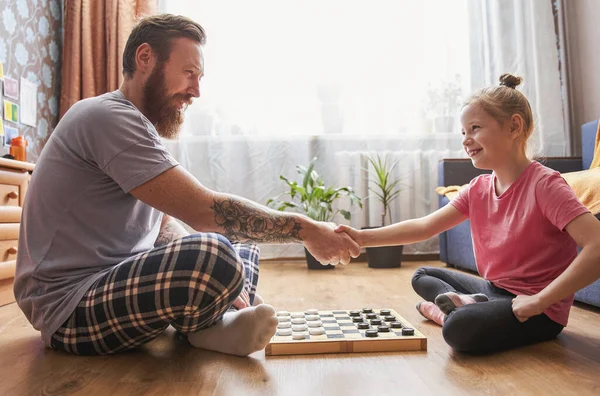 Girl sitting in front of her father and playing at checkers — Stock Photo, Image