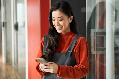 Akıllı telefon kullanarak koruyucu maske takan güzel öğrenci kız.