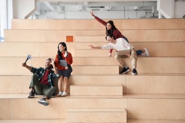 Yakışıklı, çok kültürlü öğrenci, grup arkadaşlarıyla selfie çekiyor.