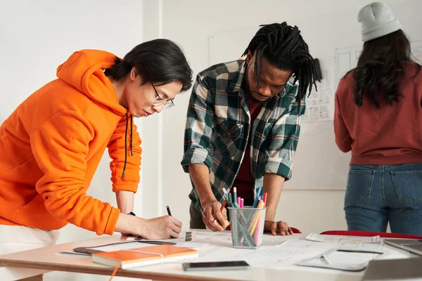 Young multiracial future designers putting on the table icons