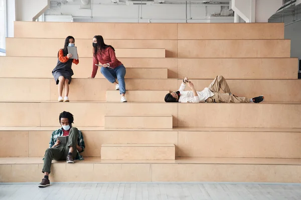 Grupo de amigos ou estudantes sorriem alegremente enquanto estão sentados nas escadas — Fotografia de Stock