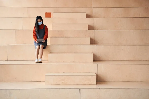 Junge Frau mit Schutzmaske verbringt Freizeit auf der leeren Treppe — Stockfoto