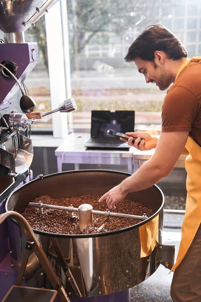 Erkek barista akıllı telefonunda yeni kavrulmuş kahvenin videosunu çekiyor. — Stok fotoğraf