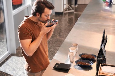 Adam kahve tanelerini dikkatlice kokluyor.