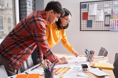 Tasarımcılar ofiste bir şey tartışıyorlar.