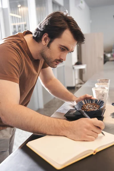 Vendedor pesando granos de café y escribiendo algo — Foto de Stock