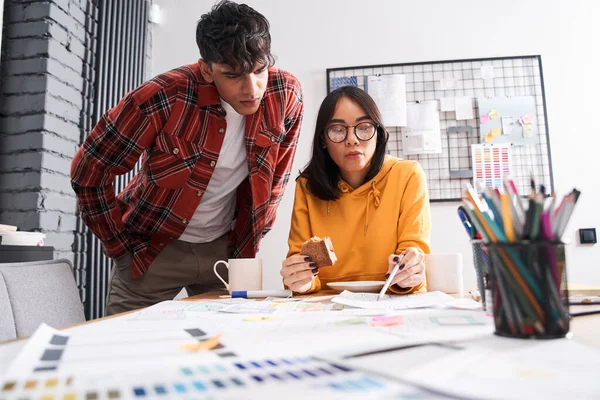 Tasarımcı, tasarım örneğiyle kağıda bakıyor