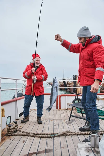 Рибалки дивляться з приглушеними очима, тримаючи величезну рибу — стокове фото