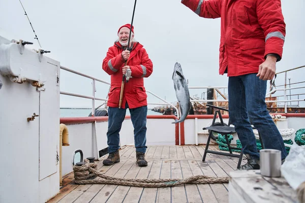 Fischer jubeln, während sie ihren Fischfang an der Angel halten — Stockfoto