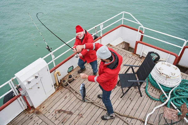 Рибалки дивляться з приглушеними очима, тримаючи величезну рибу — стокове фото