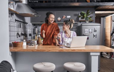 Kadınlar mutfakta yemek hazırlarken gülüyorlar.