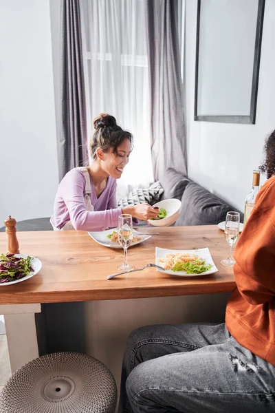 Mädchen legt frischen Salat auf ihren Teller am Tisch — Stockfoto