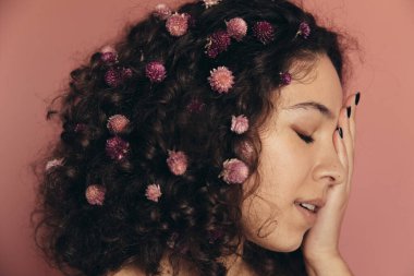 Kıvırcık kadın elleriyle yüzünü kapattı ve poz verdi.