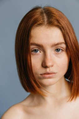 Kısa kızıl saçlı, makyajsız kadın.