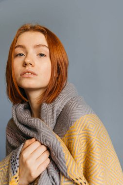 Kadın battaniyeye sarılıp kameraya bakıyor.