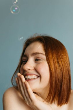 Çıplak omuzlu bir kadın başka tarafa bakıyor ve ağzı kapalı.