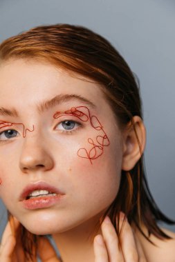 Yüzünde kırmızı iplikler olan kadın.