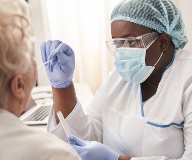 Hemşire hasta bir hastanın boğazından örnek alıyor.