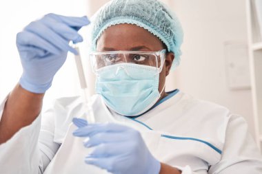 Elinde pamuklu çubuk tutan çok ırklı kadın laboratuvar asistanı.