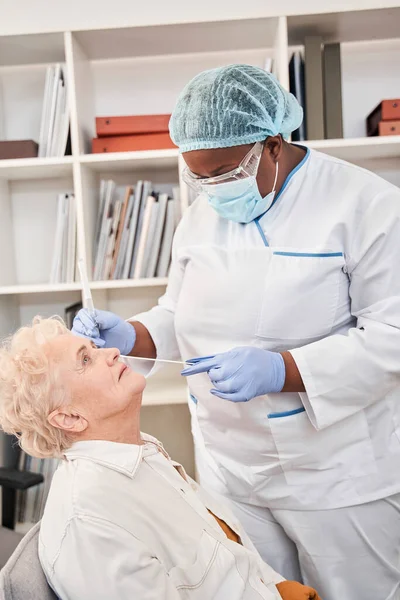Медсестра, яка приймає коронавірус або тест ДНК на зонд на носі — стокове фото
