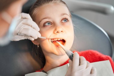 Kızın dişleri ciddi bir doktor tarafından muayene ediliyor.