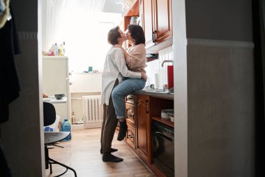 Genç lezbiyen çift evde mutfakta kucaklaşıyorlar.