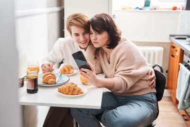 Lezbiyen çift ellerinde akıllı telefon tutarak selfie çekerken poz veriyorlar.