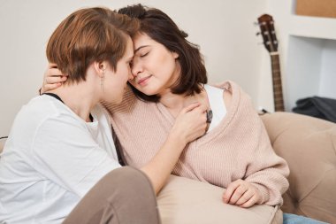 Lezbiyen çift evdeki kanepede dinlenirken birlikte vakit geçiriyorlar.