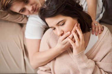 Birbirine aşık romantik lezbiyen çift kanepede sarılıp sarılıyorlar.