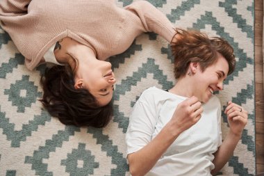 Sevimli genç bir çift yerde yatıp kahkahalarla gülüyor.