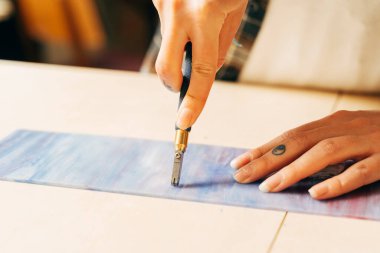 Kadın sanatçı mozaik karelere boyalı cam levhalar kesiyor.