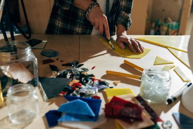 Mozaik için parçaları hazırlarken özel bir araçla cam kesen tasarımcı