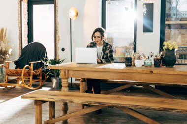 Evdeki masada oturan bir kız ve bilgisayarıyla ailesiyle ya da arkadaşıyla konuşuyor.