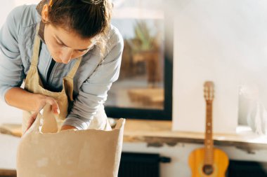 Usta atölyede yeni yapılmış kilden kavanozu tahta tahtaya koyuyor.