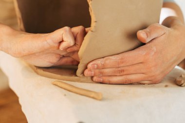 Tanımlanamayan kadın seramikçi stüdyoda kilden ot yapıyor.