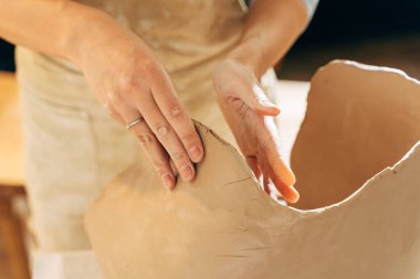 Geleneksel bir fabrikada çömlekçi çarkında seramik makaleler yapan bir kadın.