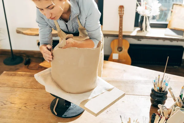 Master putting freshmade clay jar on wooden board in workshop