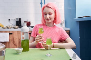 Mutfakta oturan ve kibrit içeceğinin rengine bakan kız.