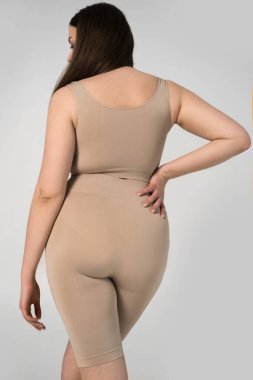 Gri arka planda poz veren esmer kadın.