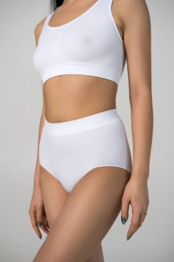 Stüdyoda beyaz iç çamaşırlarıyla poz veren güçlü vücutlu bir kadın.
