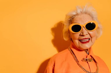 Kadın kameraya bakıyor, dişlek gülümsüyor ve zevk alıyor.