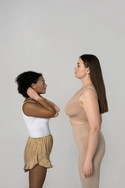Two girls with different types of skin and figure posing face to face