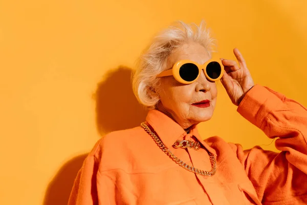 Mujer mirando hacia otro lado y tomándose de la mano sus gafas de sol —  Fotos de Stock