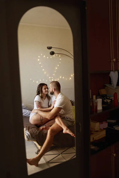 Пара обіймається в приміщенні на ліжку вдома і дивиться один на одного — стокове фото