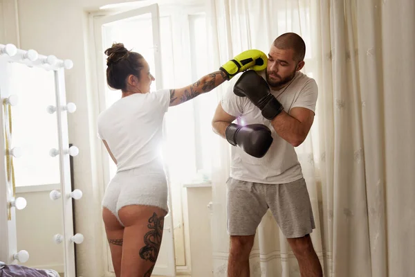 Mulher usando luvas fazendo gancho para seu namorado enquanto tem treinamento de boxe — Fotografia de Stock