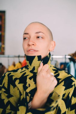 Kısa saçlı kadın ayakta duruyor ve şık paltosunun yakasına yapışıyor.