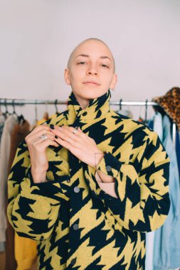 Arka planda askıyla poz verirken şık bir ceket giyen kadın.